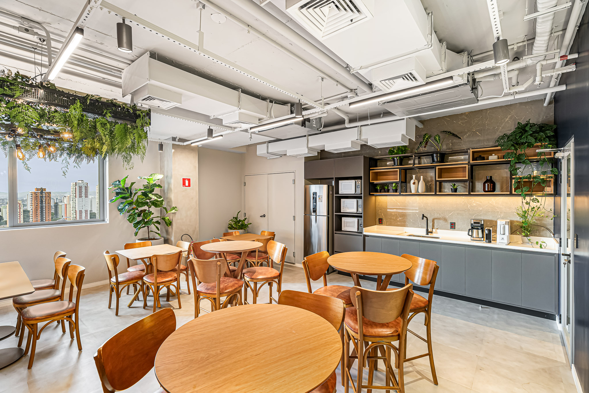 Cafeteria interna com marcenaria cinza e vista da cidade