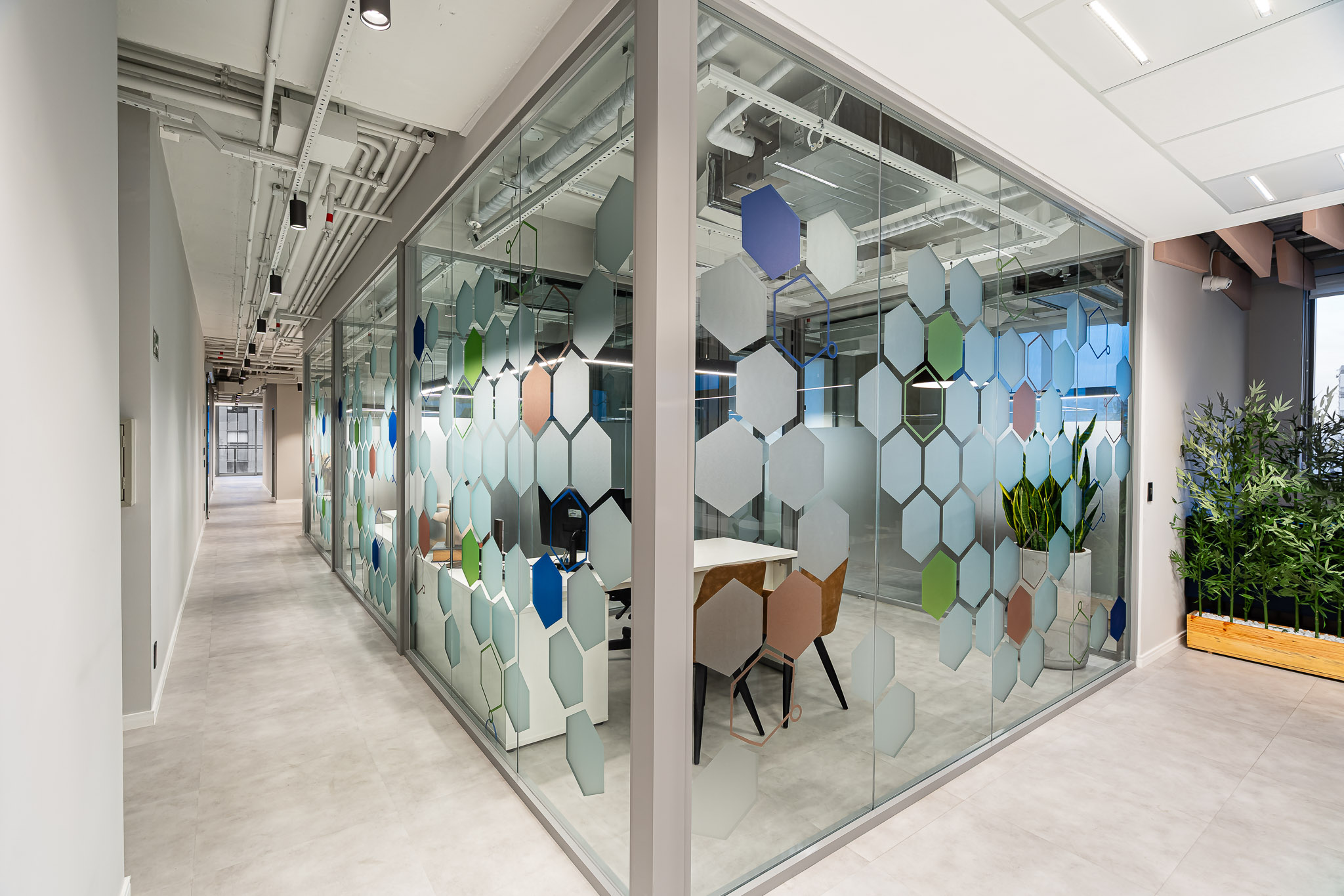 Circulação com divisórias de vidro estampadas com hexágonos coloridos