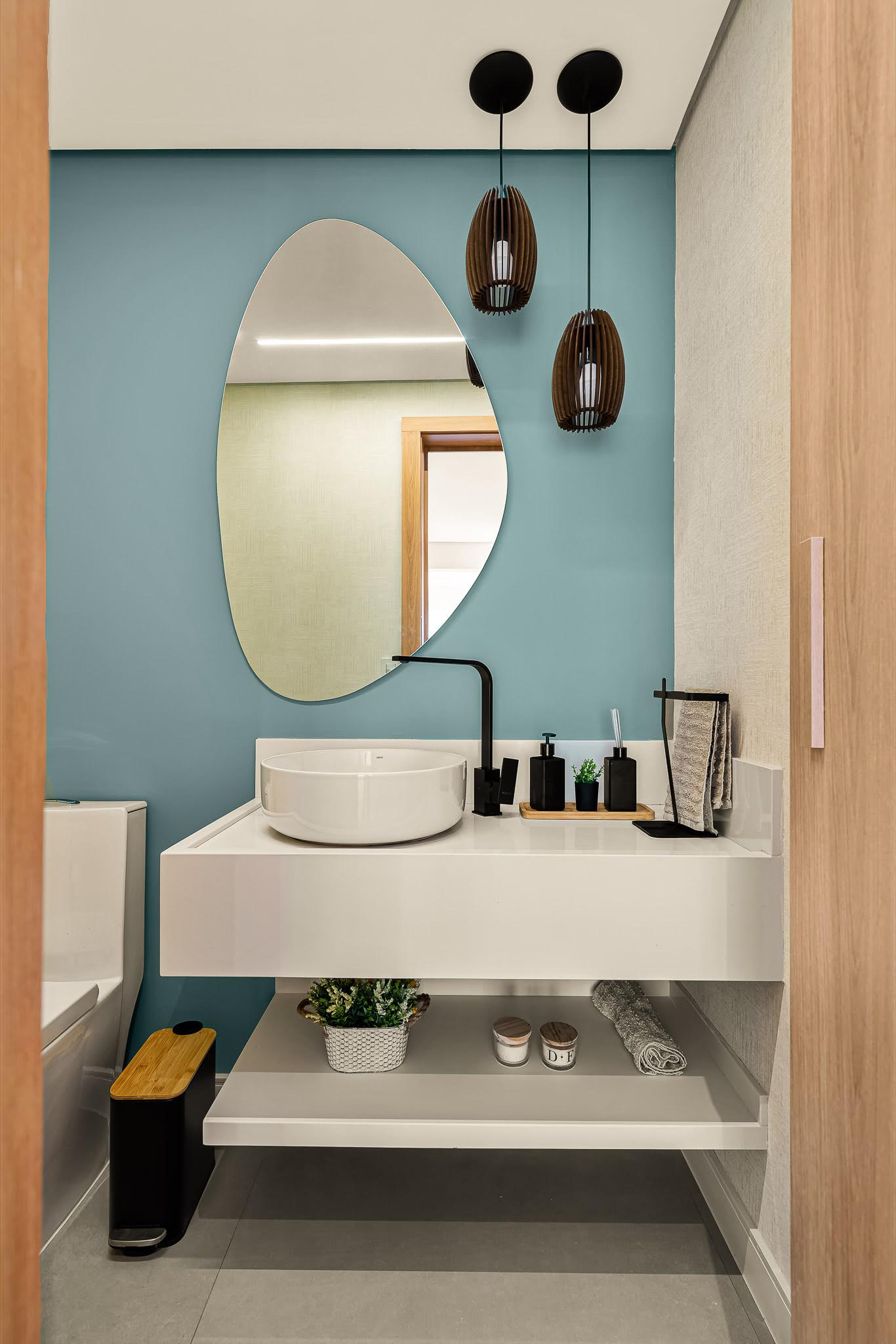 Lavabo com espelho oval orgânico, pendentes de madeira, cuba branca e torneira preta