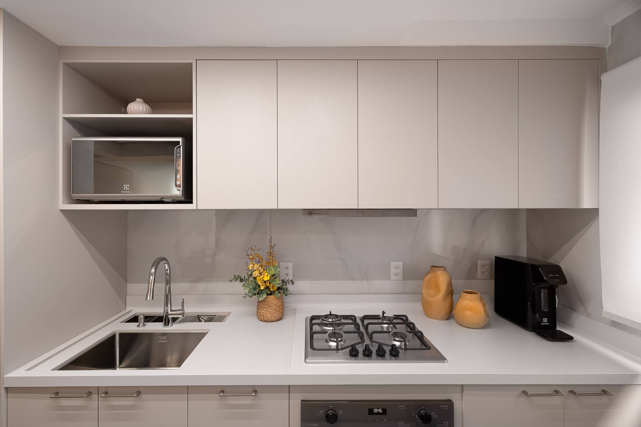 Bancada da cozinha com micro-ondas embutido e peças decorativas em âmbar