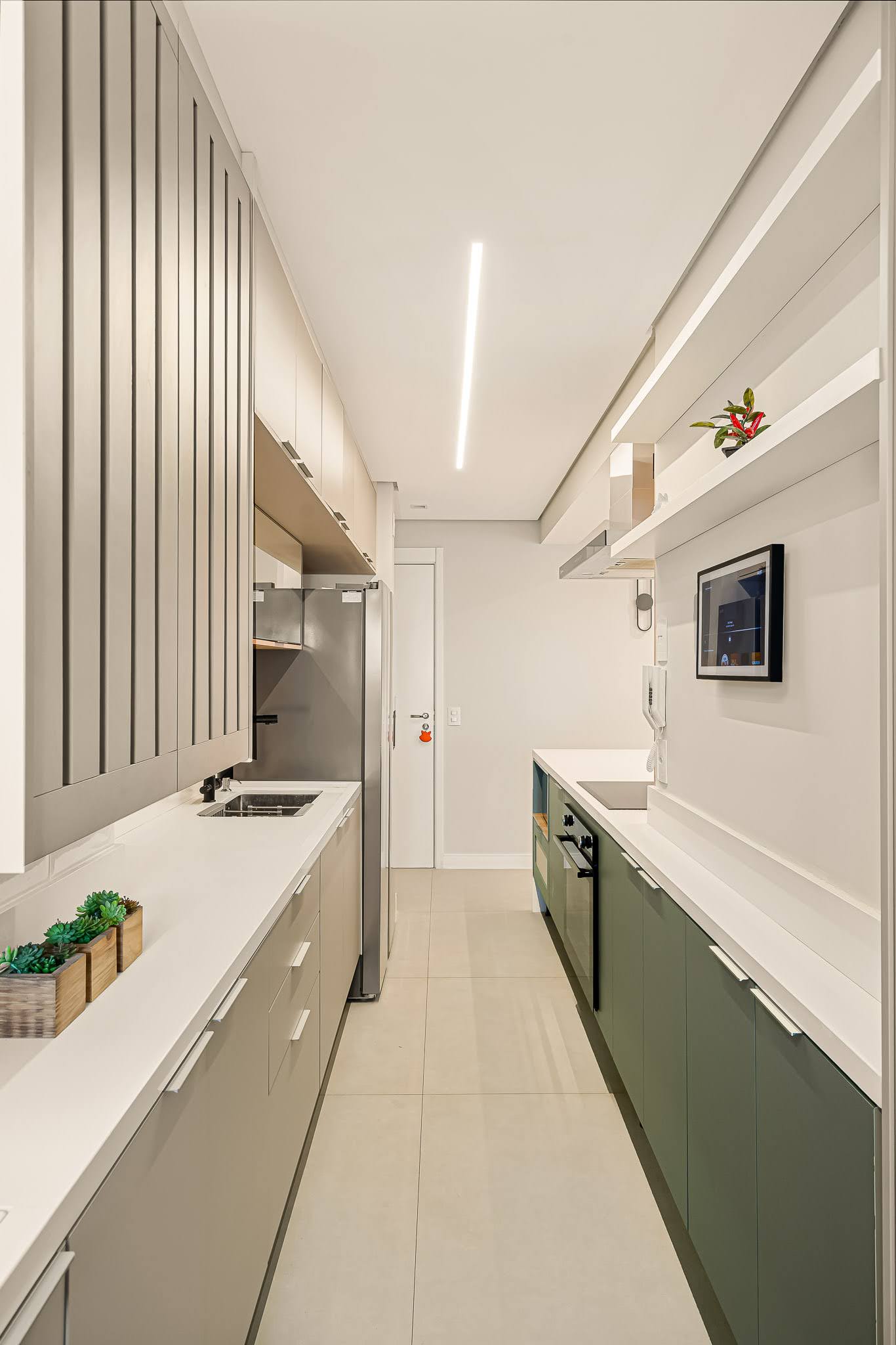 Cozinha linear com marcenaria bege e verde e iluminação linear no teto